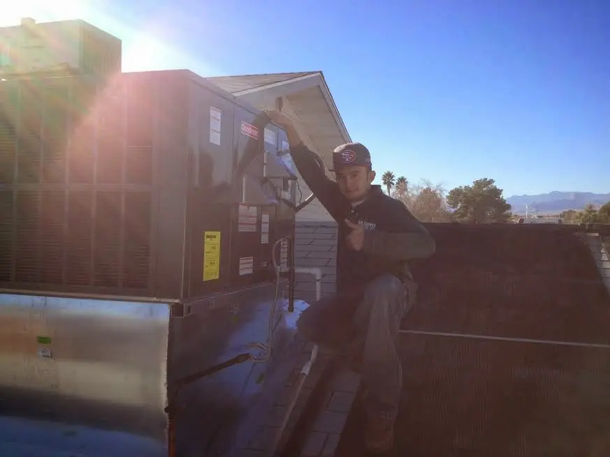 HVAC technician performing Air Duct Cleaning on a rooftop unit in Orting